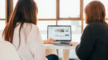 two women talking while looking at laptop computer