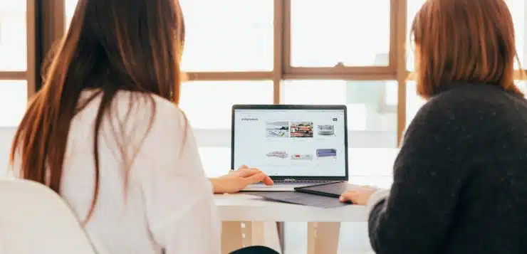 two women talking while looking at laptop computer