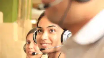 woman in black headphones holding black and silver headphones